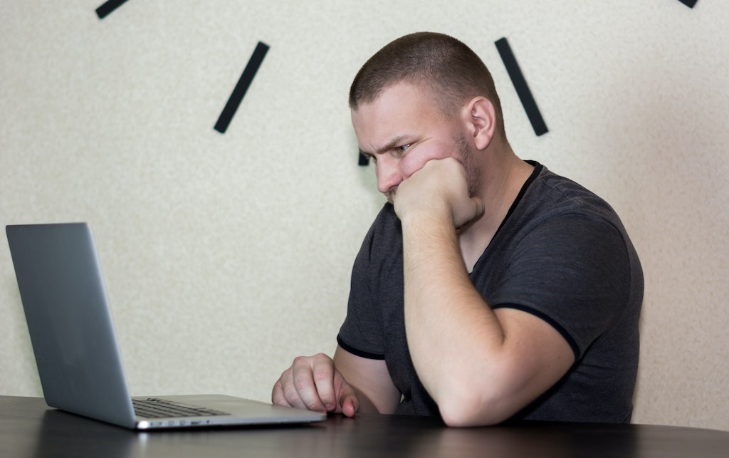 Man with fist on chin looking at computer.