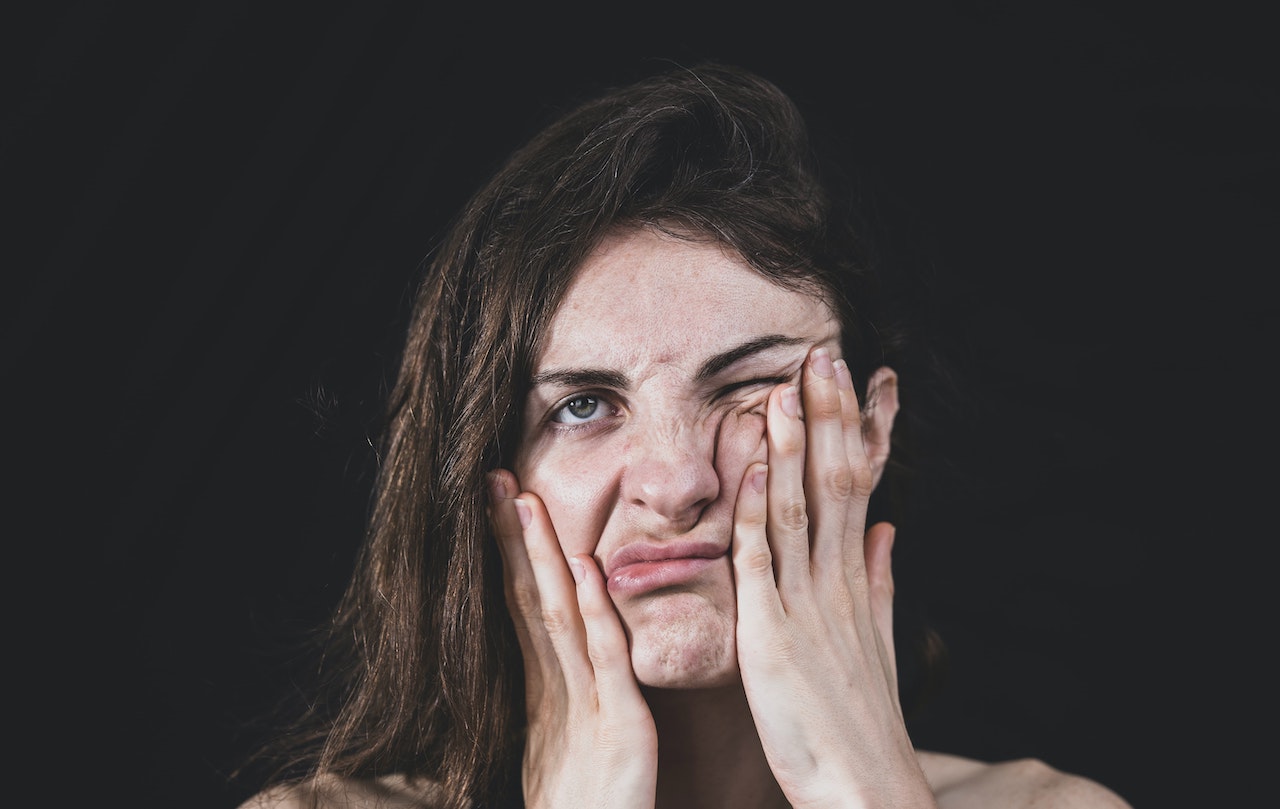 Woman with hands on face looking stressed out.