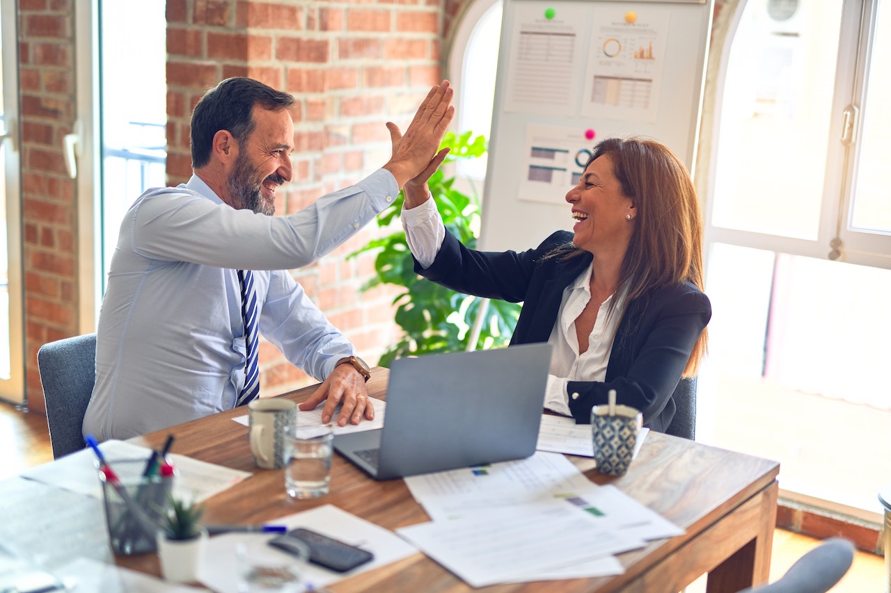 Man giving woman high five, illustrating favoritism at work.