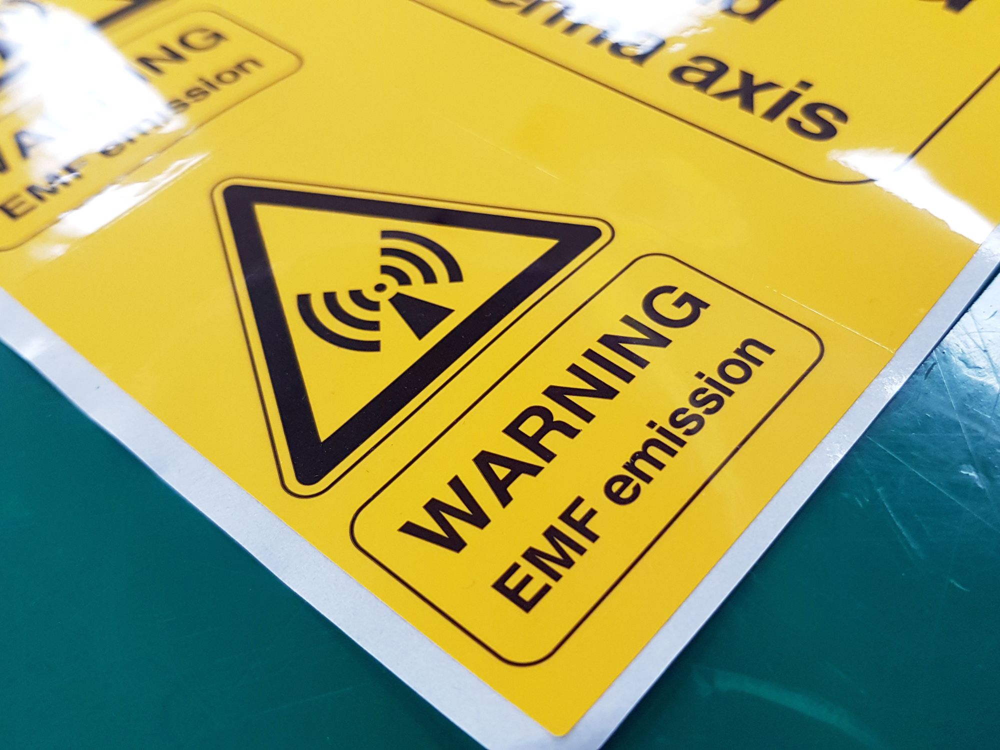 Photo of yellow warning label that reads EMF emission to illustrate safety signs and labels.