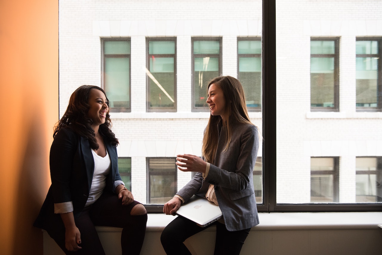 Two women talking and listening in an office window