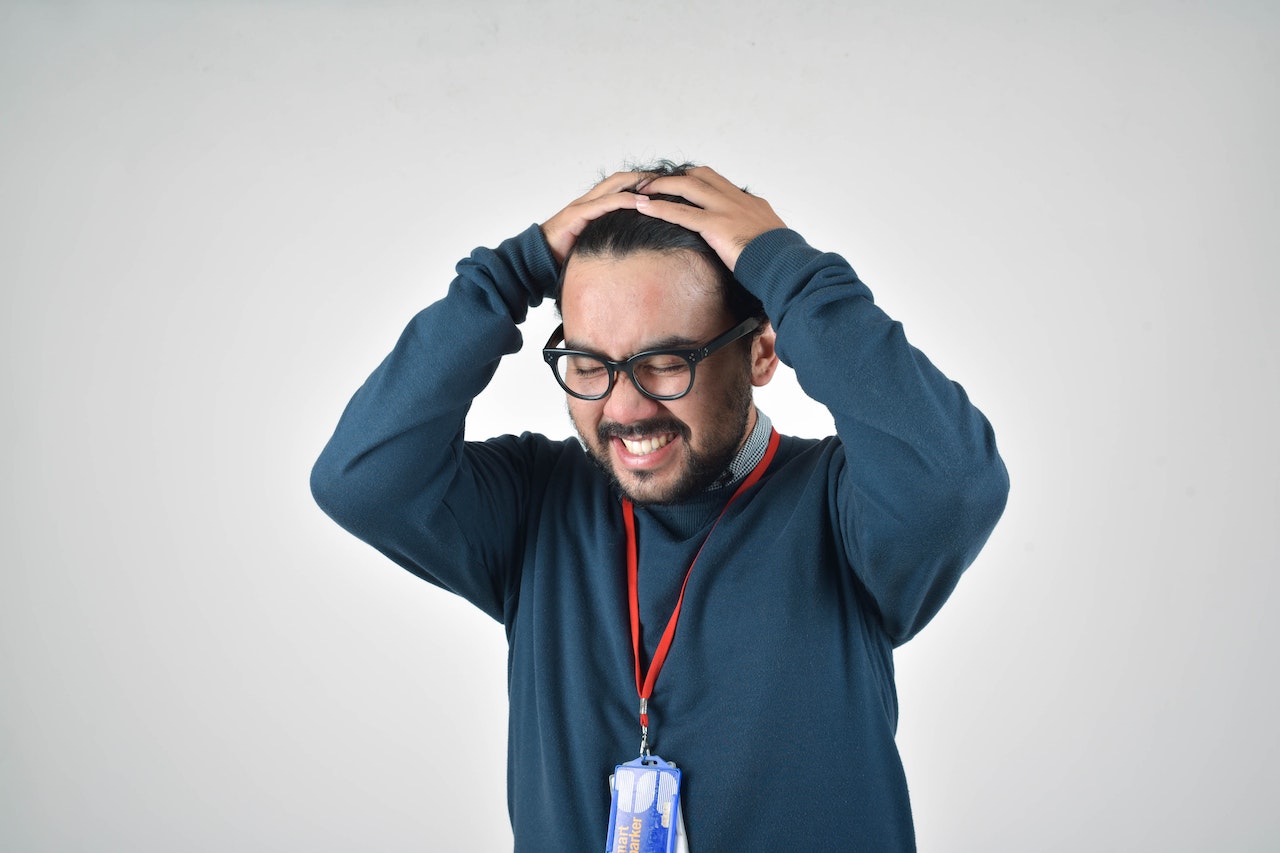 Man grabbing his head to illustrate job stress.