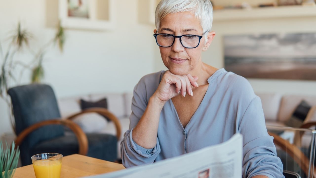 Photo of white haired woman reading paper to illustrate age discrimination.