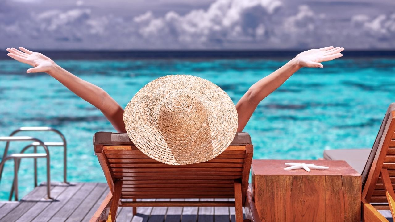 Photo of woman on lounger at ocean illustrating best job benefits.