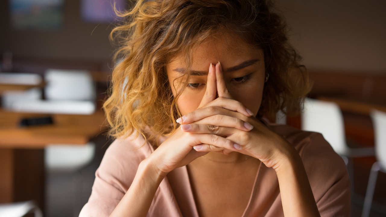 Job Burnout Photo of stressed out woman holding hands on face to illustrate job burnout.
