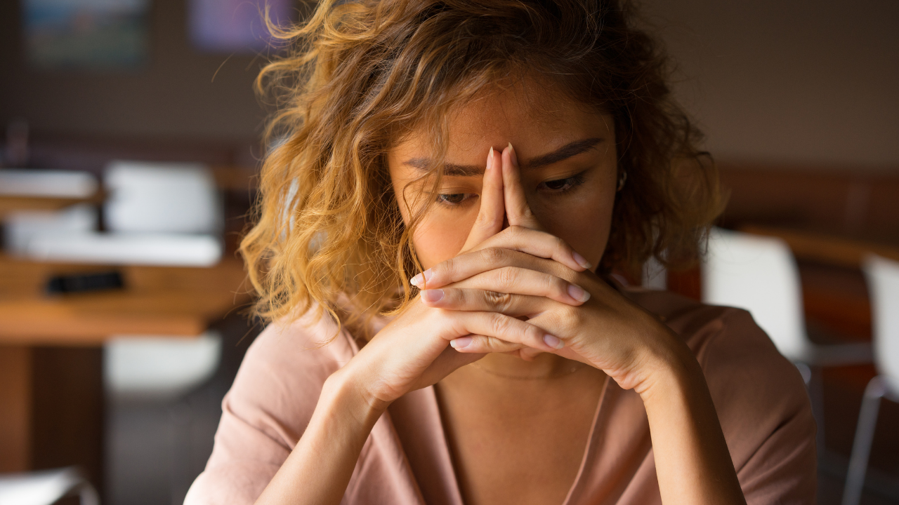 Photo of stressed out woman holding hands on face to illustrate job burnout.