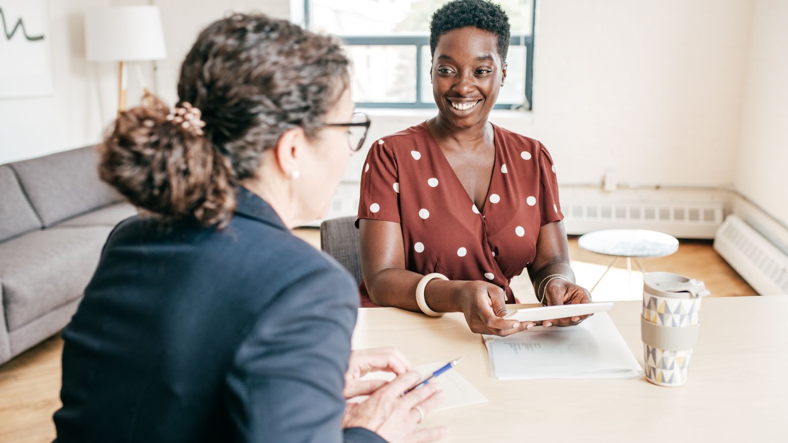 Photo of two women talking at a table to illustrate Mentoring a New Employee