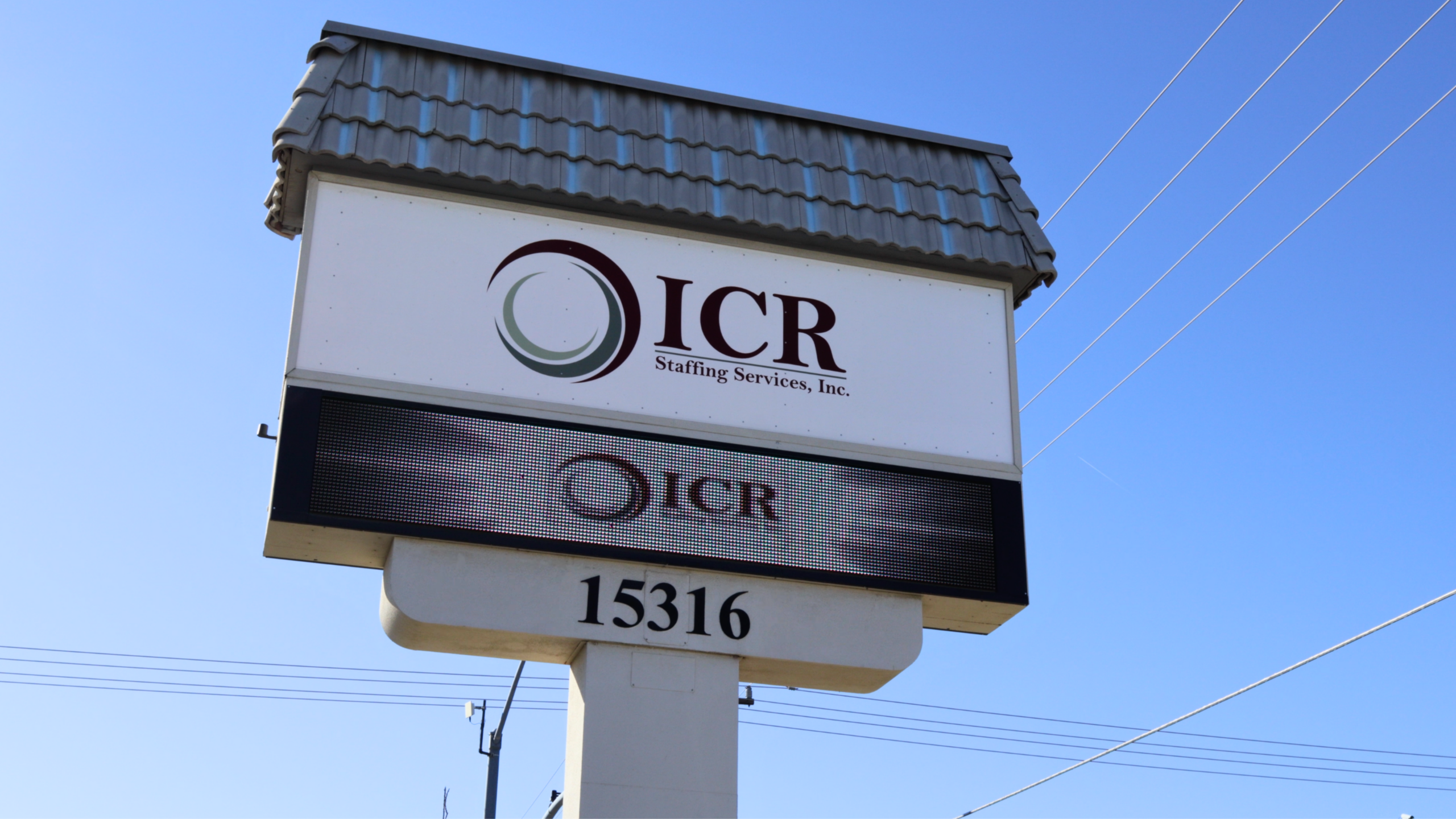 Four individuals standing together inside the ICR Staffing Services office, smiling in front of the ICR logo.