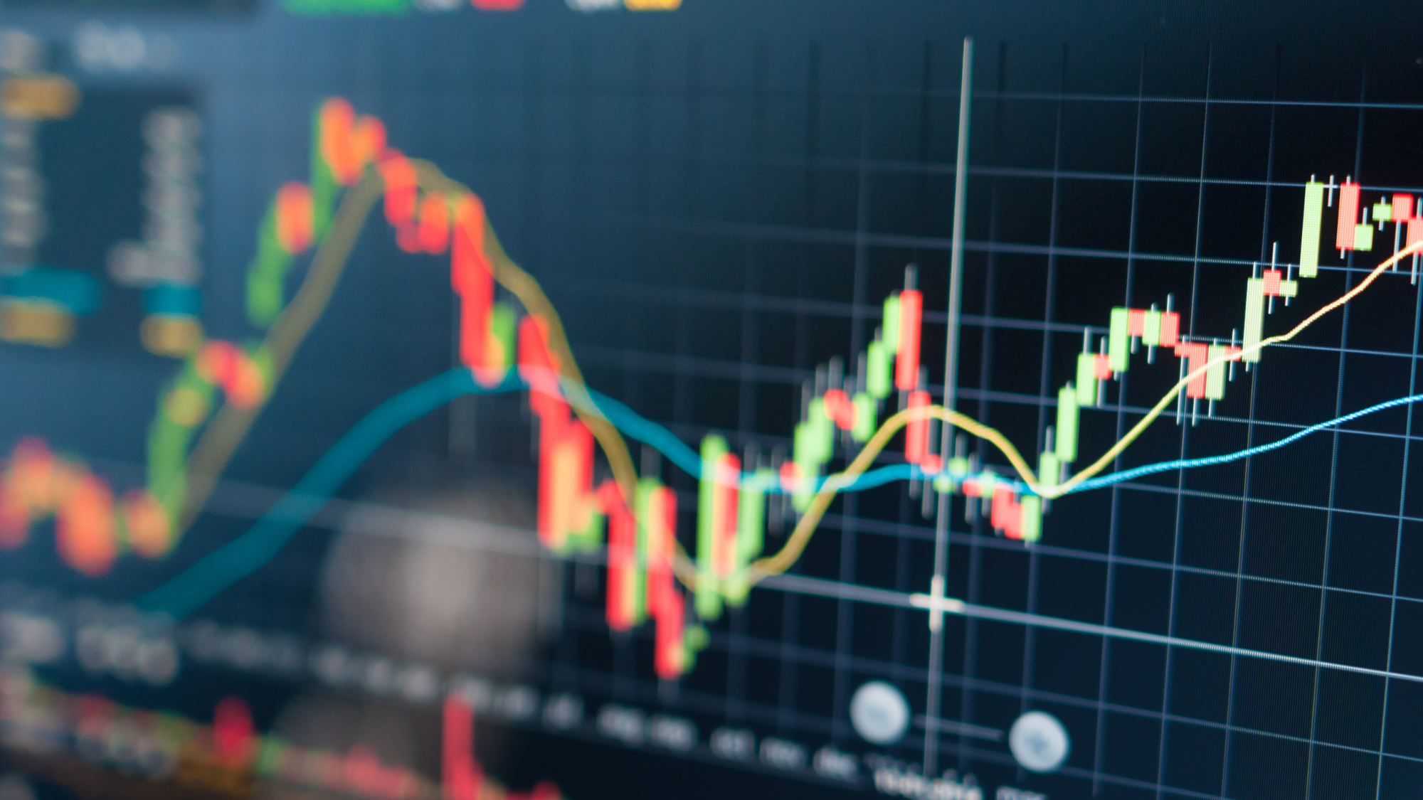 Close-up of a digital financial market chart displaying colorful candlestick patterns, trend lines, and price movements on a dark background. The graph illustrates market fluctuations, economic trends, investment performance, or labor market data analysis.