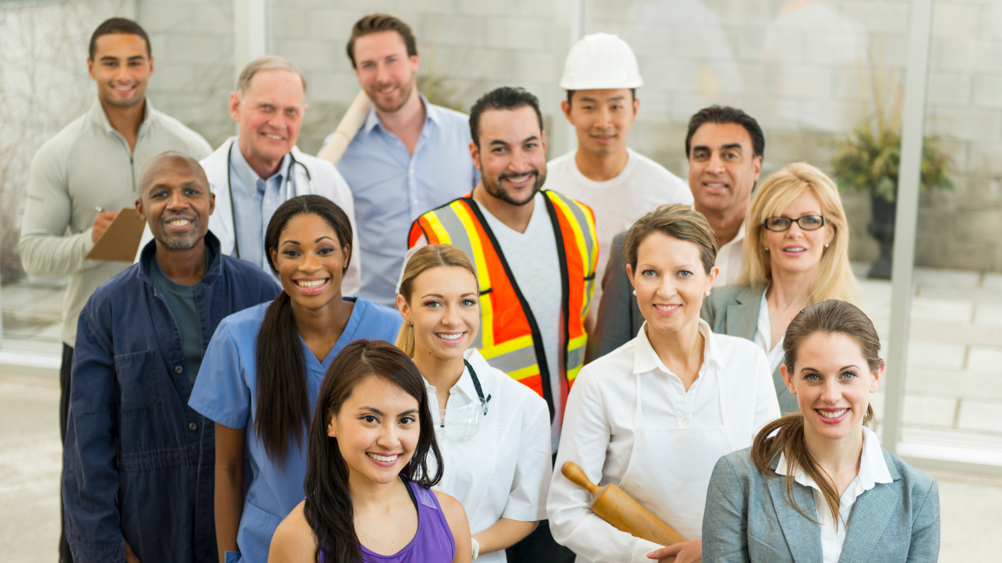 Diverse group of professionals from healthcare, construction, skilled trades, business, and industrial fields smiling together.