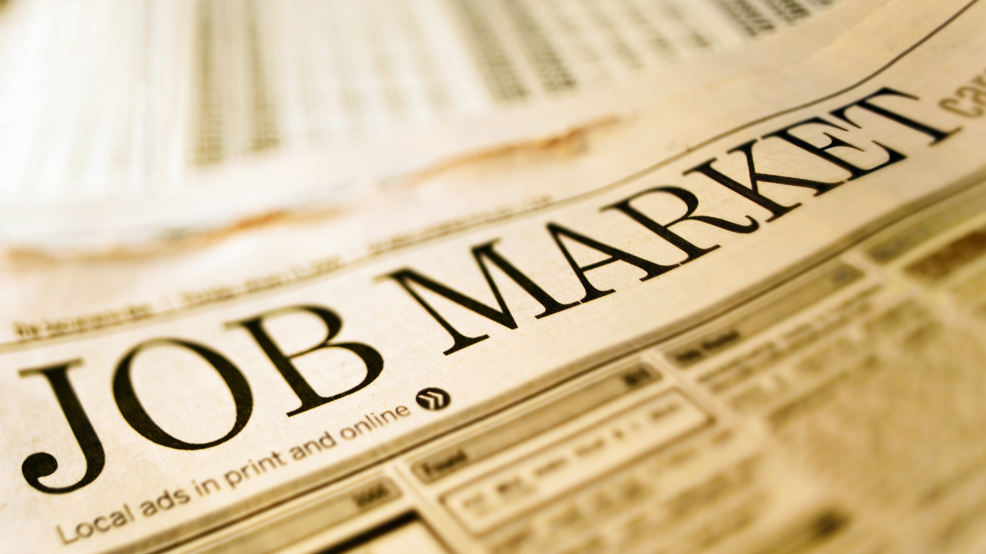 Close-up of a newspaper with the bold headline "JOB MARKET" in focus.